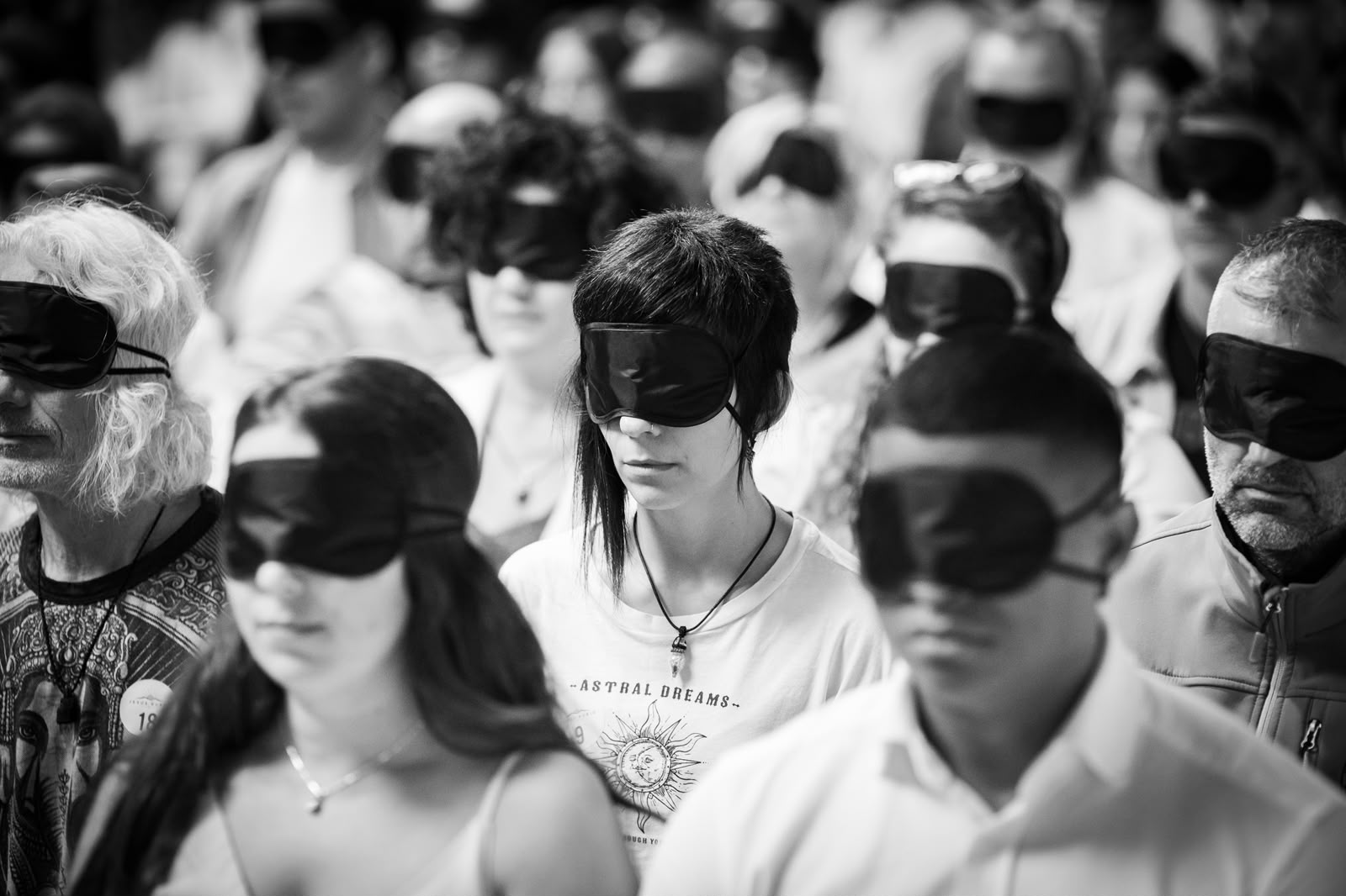Personas con antifaz en silencio, en blanco y negro, durante una experiencia de sonido